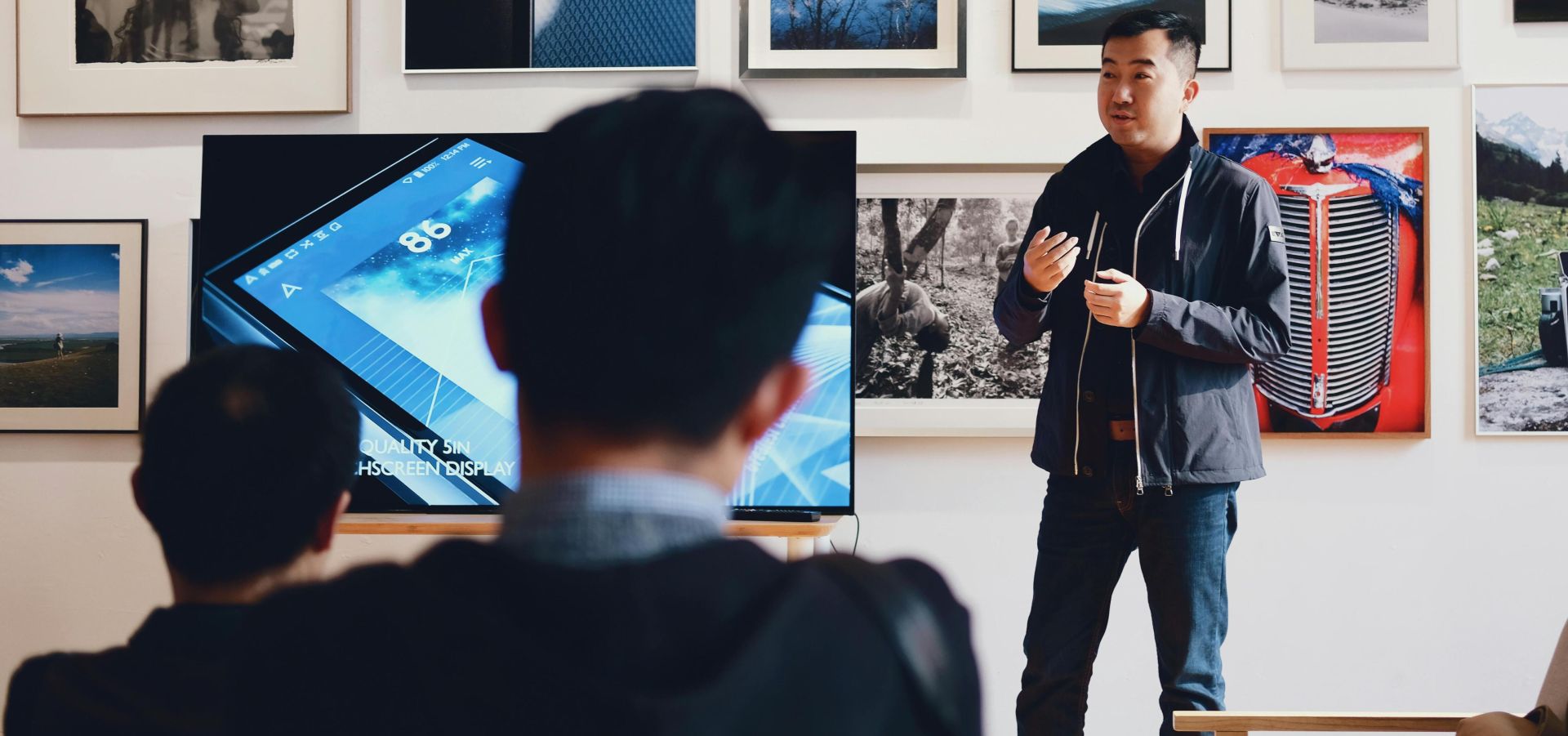 Man giving a presentation in a modern art gallery setting, engaging audience.